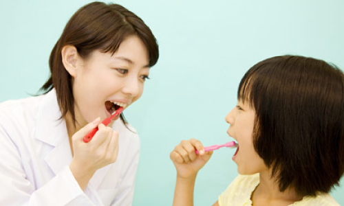 子どもと歯磨きをする女性の歯科医師